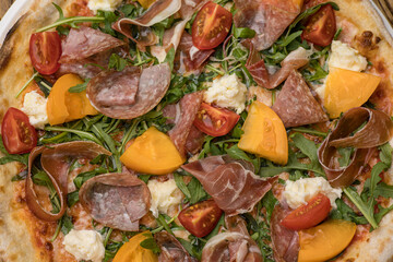 Delicious pizza with meat and yellow tomatoes 