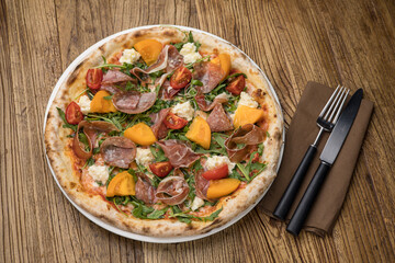 Delicious pizza with meat and yellow tomatoes 