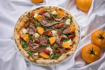 Delicious pizza with meat and yellow tomatoes 