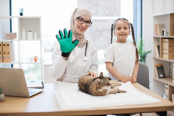 Girl and vet in pet grooming glove smiling at camera