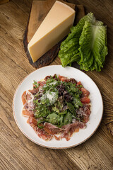 delicious salad with parmesan, jamon, tomatoes on a white plate 