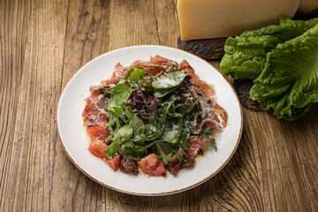delicious salad with parmesan, jamon, tomatoes on a white plate 