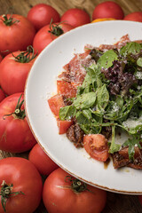 delicious salad with parmesan, jamon, tomatoes on a white plate 