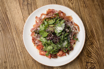 delicious salad with parmesan, jamon, tomatoes on a white plate 