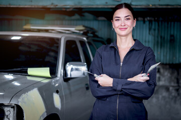 Portrait of beautiful happy smiling female auto mechanic in uniform standing arms crossed near vehicle at garage, technician woman worker repairing customer car at automobile repair service center.