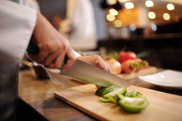Hands of cook chopping bell pepper when cooking main course