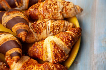 Chocolate croissants or croissant with nut crumbs on a plate. Breakfast on the table. Sweet baking dessert for coffee.