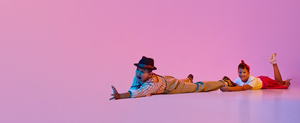 Emotional dance. Children, boy and girl in retro clothes performing against pink studio background...