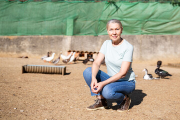 woman farmer crouched against the background of the poultry yard