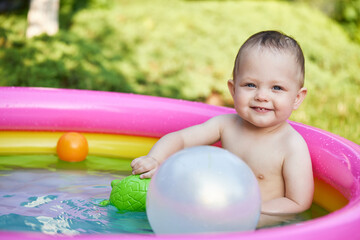 Fototapeta na wymiar cute baby girl swimming in kid inflatable pool