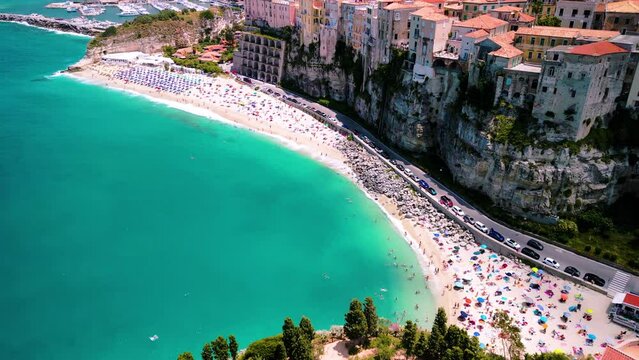 Drone aerial view of turquoise crystal clear waters and famous cliiftop town with colorful houses Tropea, Italy	