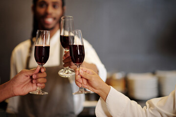 Team of kitchen workers toasting with glasses of wine after finishing long shift