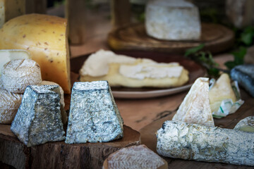 Large choice of French ripened cheese on a wooden rustic board