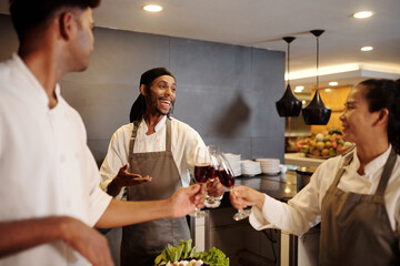 Team of joyful cooks drinking wine when celebrating restaurant opening