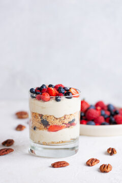 Trifle dessert in a glasses with berries, nuts, whipped cream and biscuit. Healthy food, sugar, gluten and lactose free.