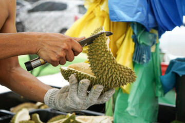A man cuts open a durian at a fruit stall.