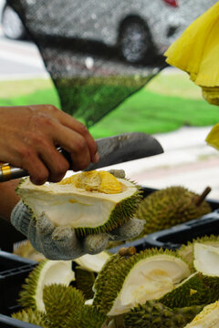 A man cuts open a durian at a fruit stall.