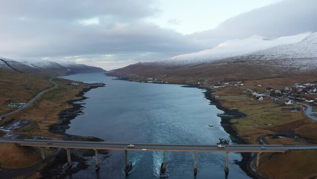 Faroe Islands 4K Aerial of Bridge between Streymoy and Eysturoy. Slow wide pull back over bridge. Beautiful Snowy mountains in the background.