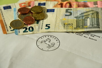 Geldscheine und Münzen auf einem Brief vom Finanzamt mit Siegel - obrazy, fototapety, plakaty