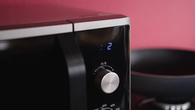 Close-up. Microwave control panel, screen timer counts down the remaining cooking time. After zeroing, the dial shows the time.