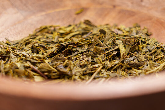 Japanese sencha dried tea leaves in rustic wooden bowl. Dried green ingredient harbal