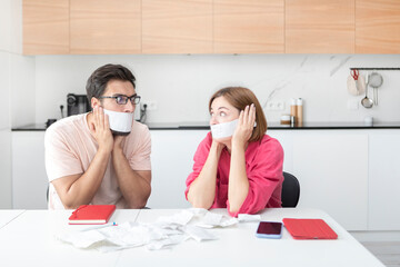 Family financial crisis concept. Shocked and stressed couple counting expenses, taxes and debts. Laptop and many bills on the table