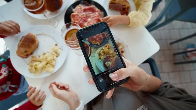 Blogger woman photographing restaurant food using mobile phone after eating