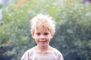Cute little boy with static electricy hair, having his funny portrait taken outdoors on trampoline