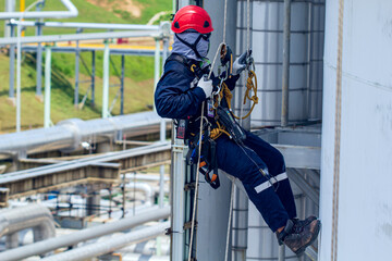 Male worker rope access height safety inspection of thickness storage oil and gas tank