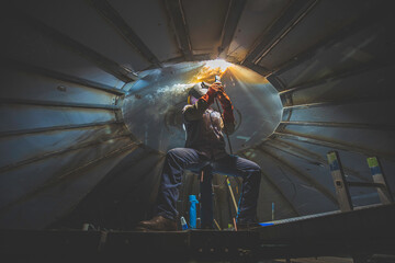 Welding male worker metal arc is part roof tank dome inside confined spaces.