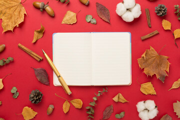 Autumn leaves with notebook on color background, top view