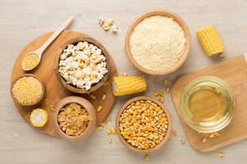Maize products with fresh corn cobs on wooden background, top view