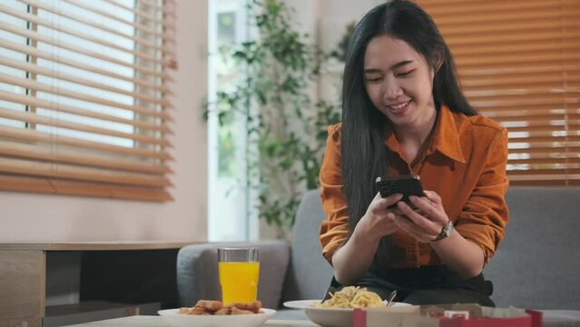 Asian woman taking picture of delicious pizza with smartphone. People and food concept