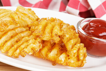 Delicious Waffle Fries isolated on a wooden background
