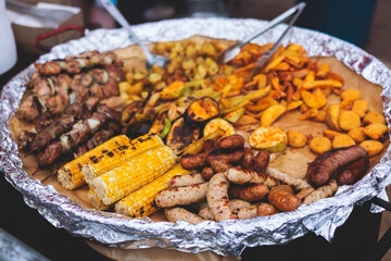 Food festival with food stall kiosk, open-air outdoor fair market, assortment of different traditional European grilled barbecued street food with sausages, bbq, chicken, pork and lamb on a large pan