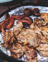 Food festival with food stall kiosk, open-air outdoor fair market, assortment of different traditional European grilled barbecued street food with sausages, bbq, chicken, pork and lamb on a large pan