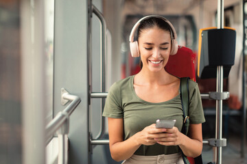 Woman Passenger Enjoying Music with Headphones and Smartphone in Tram