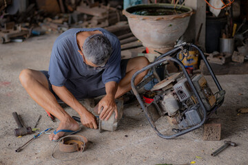 A very old and experienced craftsman sits and fixes the farmer's water pump. dress up country house...