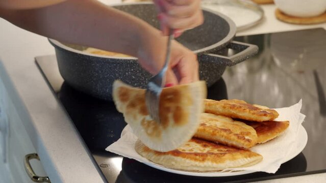 woman cooking homemade pasties frying chebureks in the kitchen at home