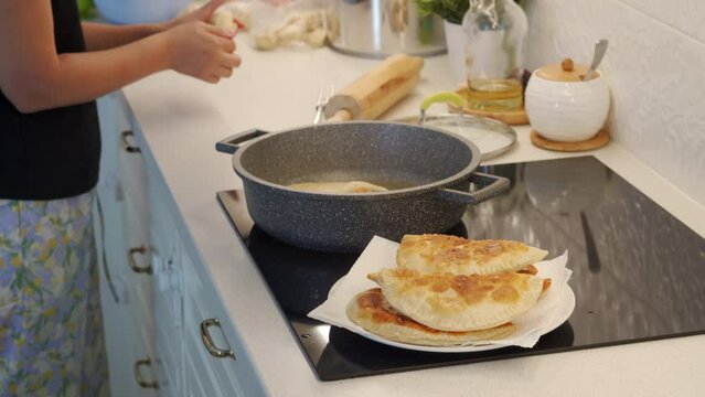 woman cooking homemade pasties frying chebureks in the kitchen at home