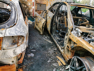 Fototapeta premium Broken and burned cars in the parking lot, accident or deliberate vandalism. Burnt car. Consequences of a car accident. Damaged by arson. Dump of civilian vehicles shot by Russian troops in Ukraine.