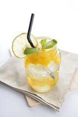 cold iced summer mango peach fruit juice with lemon mint leaf with red cherry in cocktail glass black straw on grey cloth white background asian beverage halal food drink menu for hotel bar cafe