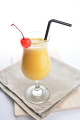 cold iced summer orange mango fruit juice with red cherry in cocktail glass black straw on grey cloth white background asian beverage halal food drink menu for hotel bar cafe