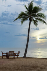 Fototapeta na wymiar dining table sea view on sand beach with sunset, wood chairs and table