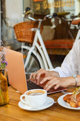 An independent worker sits with a laptop in a summer playground cafe