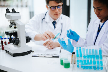 Focused mature male doctor and African female nurse look at tablet and laptop screen discuss anamnesis together. Concentrated diverse medical professionals