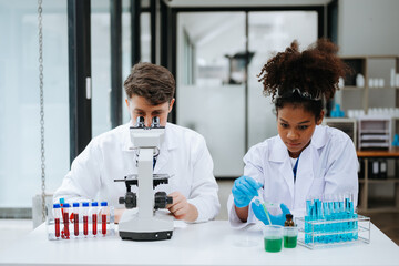 Focused mature male doctor and African female nurse look at tablet and laptop screen discuss anamnesis together. Concentrated diverse medical professionals