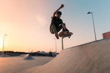 young man skates in a skate park at sunset