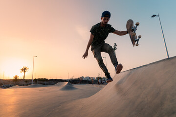 young man skates in a skate park at sunset
