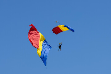 Skydivers descend gracefully from the vast expanse of the sky, their parachutes unfurling like...